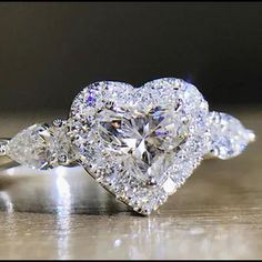 a heart shaped diamond ring with three pear shaped diamonds