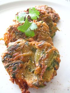 two fritters on a white plate topped with cilantro and parsley