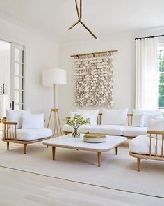 a living room filled with white furniture and a large painting on the wall behind it