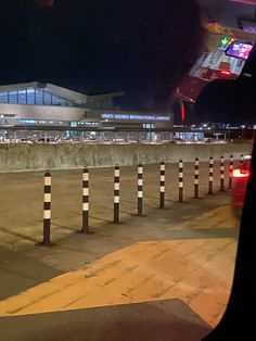 an airport at night with traffic lights on the ground and cars parked in front of it