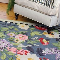 a blue rug with flowers on it in front of a couch