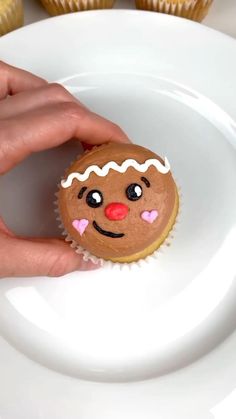 a hand holding a cupcake on top of a white plate