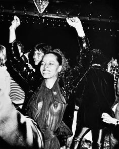 black and white photograph of people dancing at a party with one woman holding up her hand