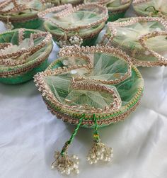 several green and gold baskets with tassels on them sitting on a white table cloth