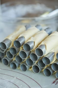 several metal tubes stacked on top of each other in front of a plate with utensils