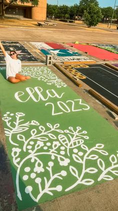 a woman is sitting on the ground with her hand up in the air and painted chalk