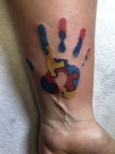 a person's foot with a colorful puzzle piece tattoo on the left side of their leg