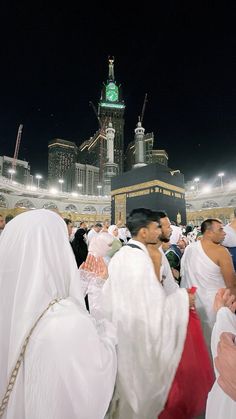 many people dressed in white are standing outside at night with the clock tower in the background