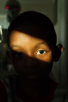 a young boy looking at the camera with his eyes wide open and one eye partially closed