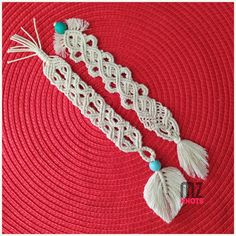 two white crocheted laces with tassels and beads on a red surface