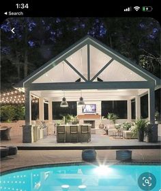 an outdoor living area with a pool and patio furniture at night, lit up by string lights