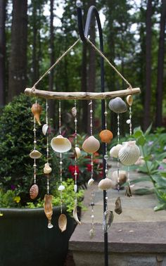 a wind chime with seashells hanging from it's sides in a garden