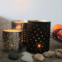 three candles are sitting on a table next to shells and fruit