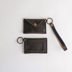 two leather wallets and a keychain on a white surface