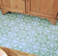 a bathroom with green and white tiles on the floor next to a wooden sink cabinet