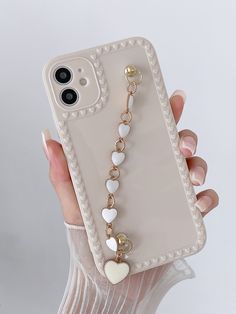 a person holding up a phone case with heart charms on it