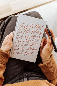 a woman is holding a book with writing on it and she has a pen in her hand