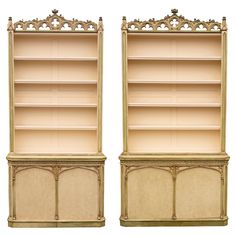 two large bookshelves with ornate carvings on the top and bottom, both in gold