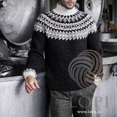 a man standing next to a metal tank wearing a black and white knitted sweater