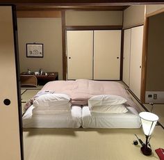 a bed sitting in the middle of a room next to a lamp on top of a table