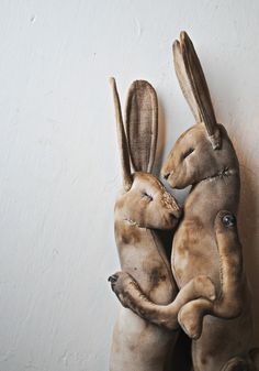 two stuffed rabbits are hugging each other on the wall in front of a white wall