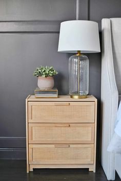 a nightstand with a lamp and a plant on it