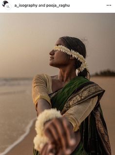 a woman standing on top of a beach next to the ocean holding something in her hand