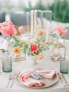 the table is set with candles and flowers in vases, plates, napkins and silverware