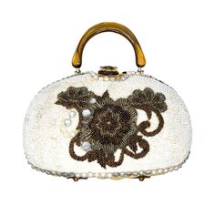 "Vintage 1950's embellished handbag by Adele has a natural woven wicker body. The front of the purse is encrusted in crème glass seed beads with a large bronze flower in the center. There is a row of large faux pearls and AB crystals along the outside. The frame and top handle are made from swirled butterscotch Lucite. It had a gold tone rolling clasp and four brass feet. Interior is gold satin with one gold foil pocket and one metal zipper pocket. Purse measures 9\" wide by 6.5' tall by 3\" acr Luxury Embellished Cream Bags, Handheld Beaded Beige Evening Bag, Beige Beaded Handheld Evening Bag, Beige Embellished Rectangular Evening Bag, Luxury Beige Embellished Bags, Embellished Beige Evening Bag, Embellished Beige Evening Bag For Events, Beige Embellished Evening Bag, Cream Evening Bag With Detachable Handle