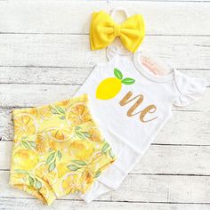 two pieces of yellow and white clothing on top of a wooden floor with a bow