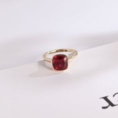 a red stone ring sitting on top of a piece of paper