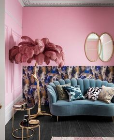 a living room with pink walls, blue couches and gold mirrors on the wall