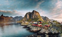 an island with houses on it and mountains in the backgrouds, surrounded by water