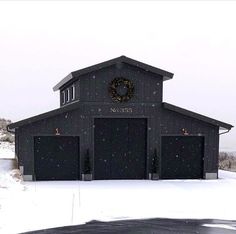 a black building with a wreath on the front and two garages in the back