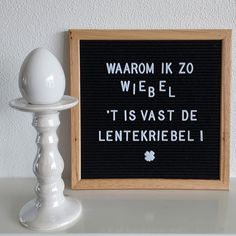 a black and white sign sitting on top of a table next to a candle holder