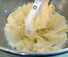 a metal bowl filled with yellow batter and a whisk in the top of it