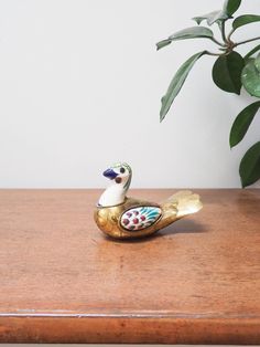 a ceramic duck sitting on top of a wooden table next to a potted plant