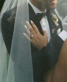 a bride and groom standing under a veil