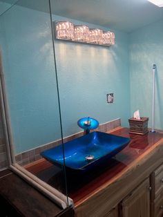 a bathroom with a blue bowl sink and wooden counter top in front of a mirror