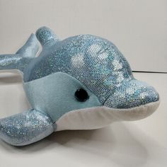 a blue stuffed dolphin with sequins on it's face