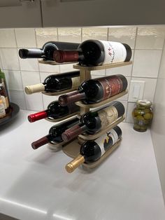 several bottles of wine are stacked up on a kitchen counter with white tile behind it