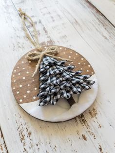 a small wooden christmas tree hanging on a white plate with polka dot ribbon and twine