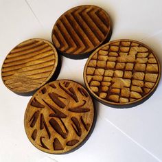 four wooden coasters with designs on them sitting on a white counter top in the shape of waffles