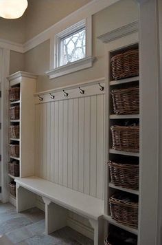 an entryway with baskets on the wall and shelves in front of it that are built into the floor