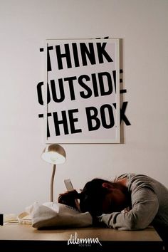 a person laying on the floor in front of a poster that says think outside the box