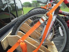 an orange bike is tied to the back of a truck