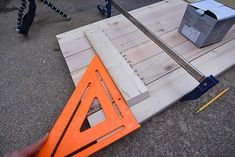 a person holding a pair of scissors next to a piece of wood and some construction equipment