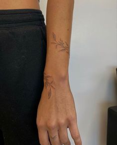 a woman's hand with a small tattoo on her left wrist and the other arm behind her