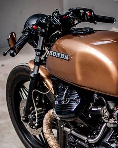 a brown motorcycle parked on top of a cement floor next to a wall and sidewalk