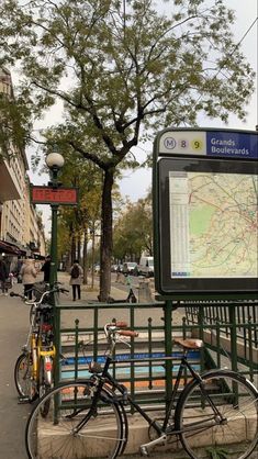 two bicycles are parked next to a bus stop with a map on the back ground